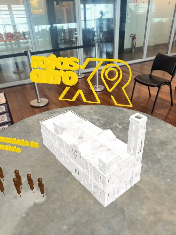 Modelo arquitetônico virtual e marca Rotas Afro XR sobrepostos ao ambiente em realidade aumentada