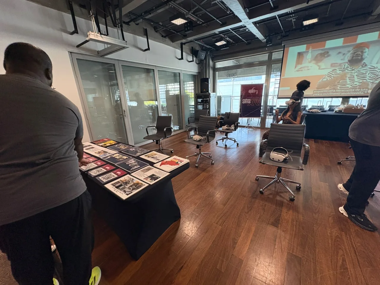 Instalação do Rotas Afro XR com cadeiras, óculos Meta Quest e projeção no Sesc Avenida Paulista