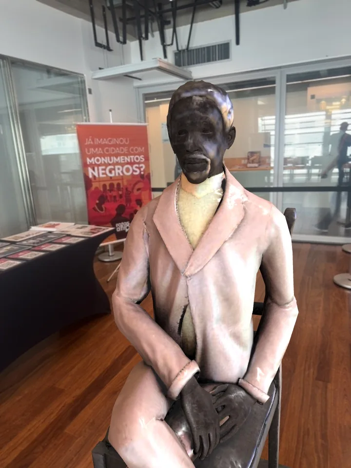 Monumento virtual de um homem sentado sobreposto ao ambiente no Rotas Afro XR