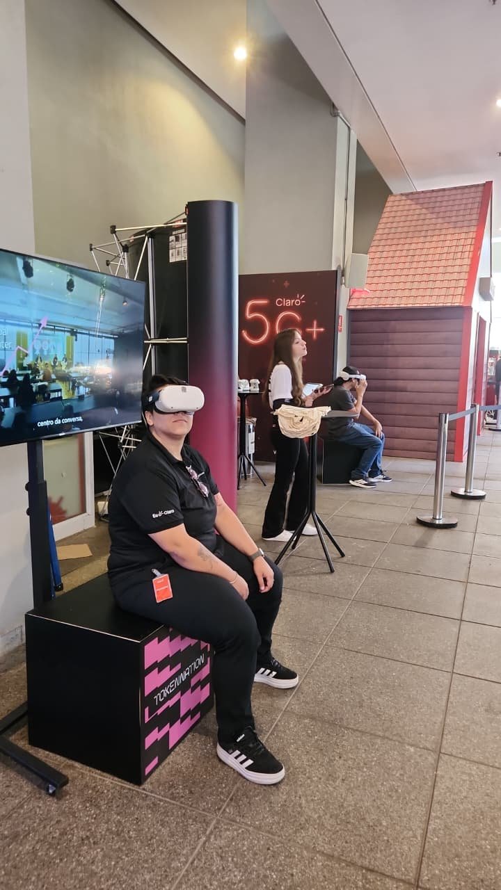Participante sentado utilizando óculos de realidade virtual junto a um monitor